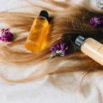 Hair care products on a bed of hair and flowers, symbolizing luxury and beauty.